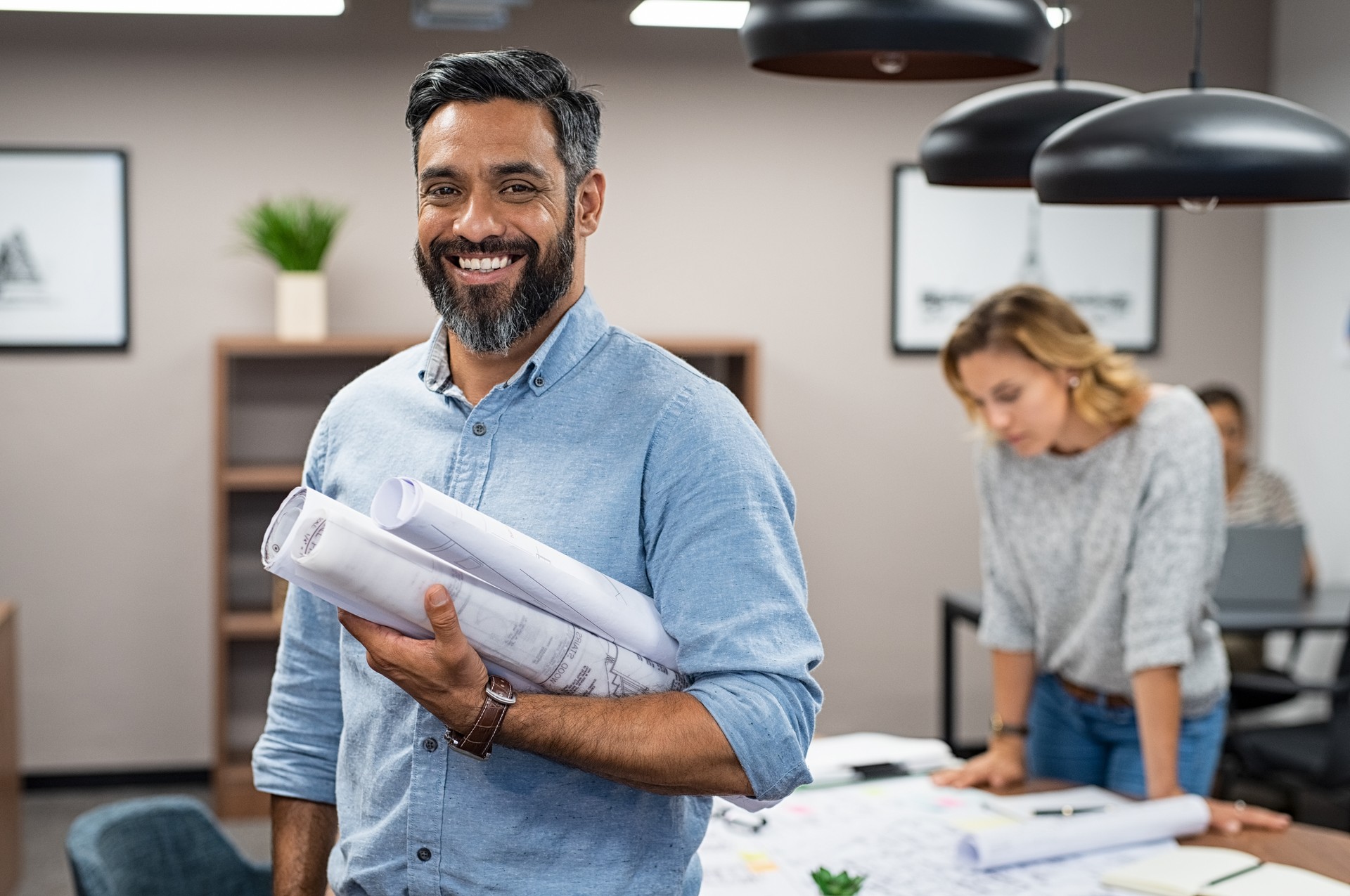 Happy latin architect holding blueprints